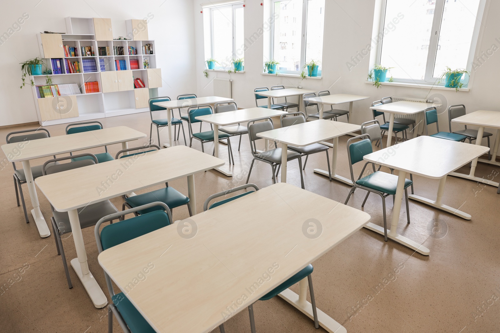 Photo of Empty school classroom with desks, windows and chairs