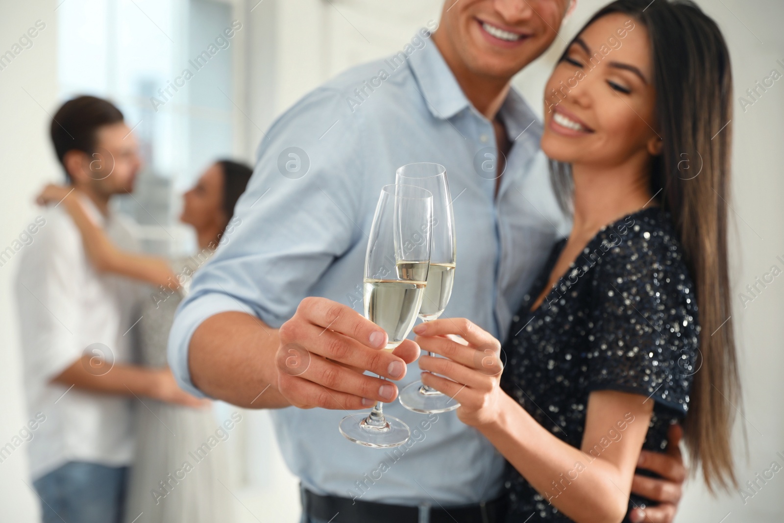 Photo of Young couple with glasses of champagne at dancing party, focus on hands