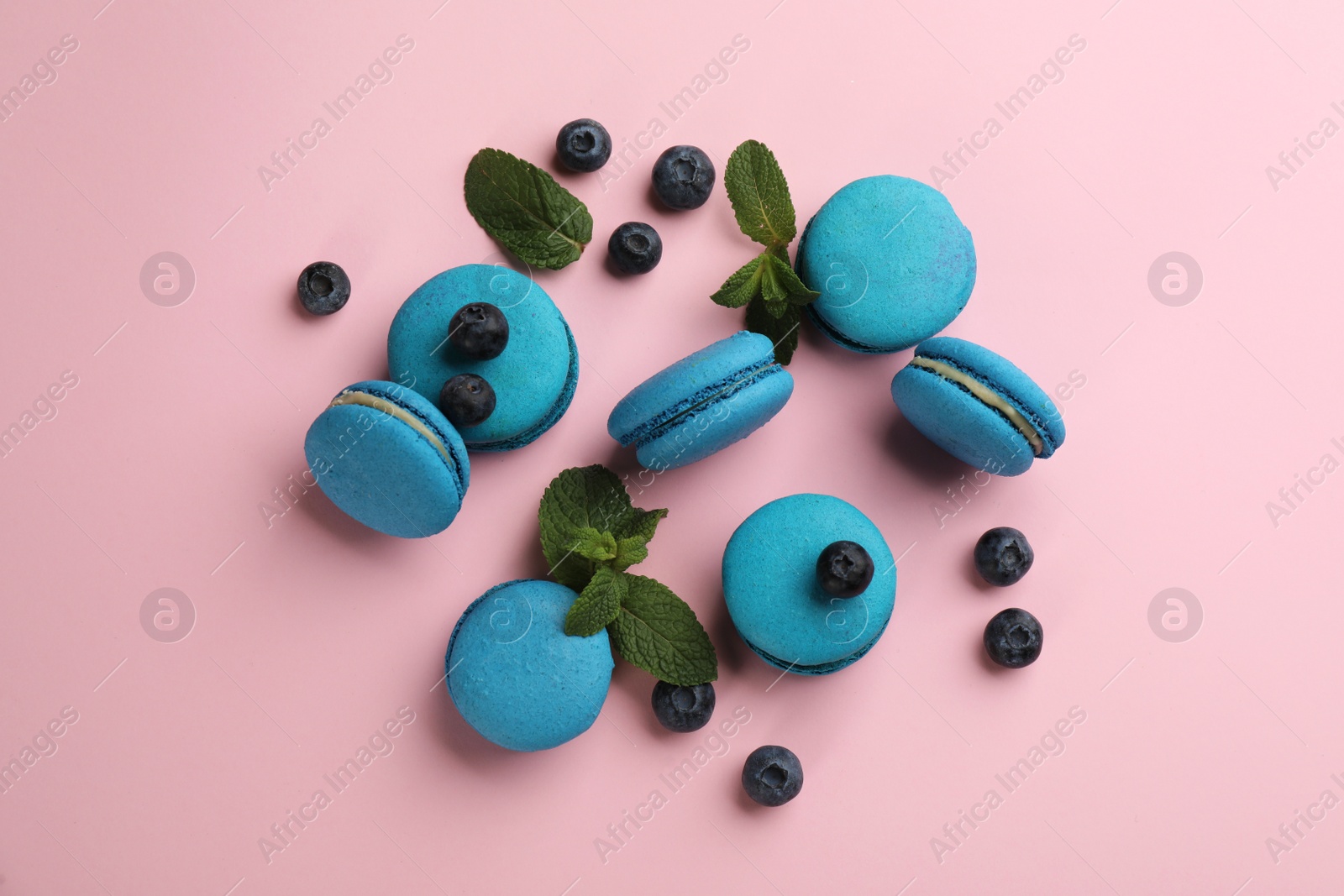 Photo of Flat lay composition with light blue macarons, mint and blueberries on pink background