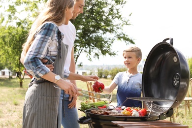 Photo of Happy family having barbecue with modern grill outdoors