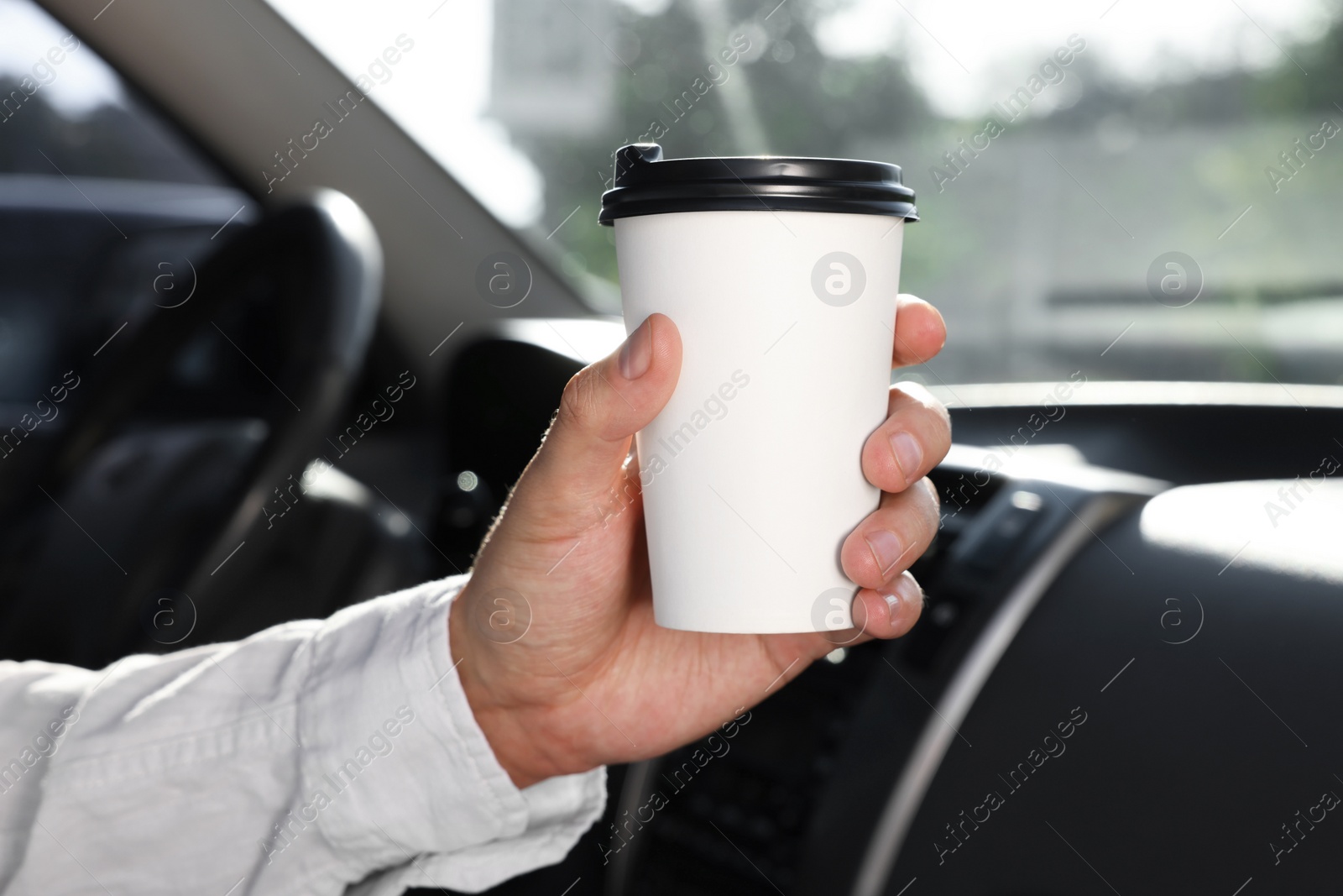 Photo of Coffee to go. Man with paper cup of drink in car, closeup