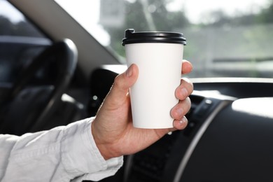 Photo of Coffee to go. Man with paper cup of drink in car, closeup