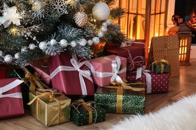 Pile of gift boxes near beautiful Christmas tree indoors