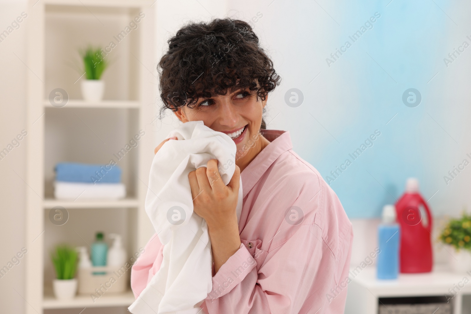 Photo of Beautiful woman with clean laundry at home