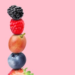 Stack of different fresh tasty berries on pink background, space for text