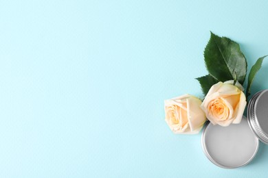 Photo of Lip balm and rose flowers on light blue background, top view. Space for text