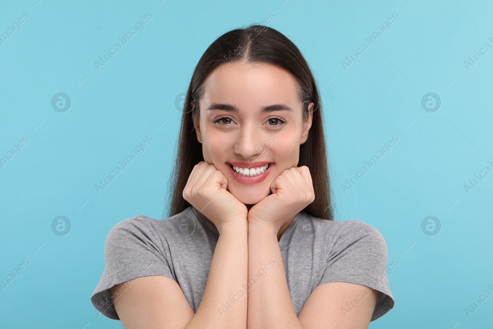 Photo of Young woman with clean teeth smiling on light blue background