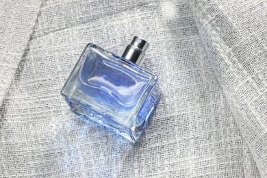 Photo of Luxury men's perfume in bottle on grey jacket, above view. Space for text