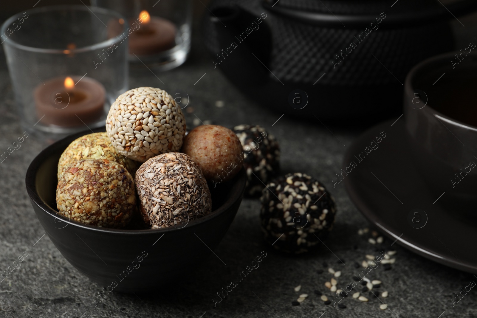 Photo of Different delicious vegan candy balls on grey table