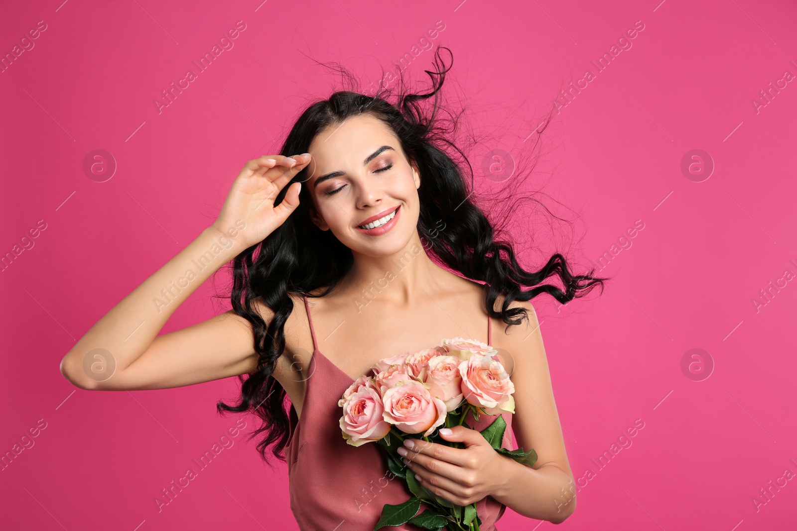 Photo of Portrait of smiling woman with beautiful bouquet on pink background