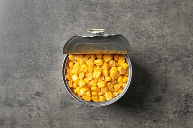 Photo of Open tin can of corn kernels on table, top view