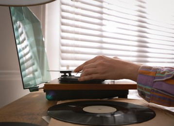 Photo of Young woman using turntable at home, closeup