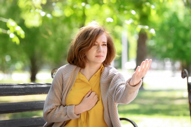 Mature woman having heart attack on bench in park