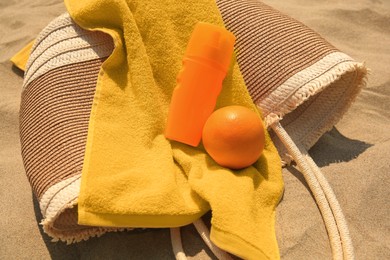 Photo of Beach bag, sunscreen and other accessories on sand