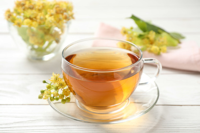 Photo of Cup of tea and linden blossom on white wooden table