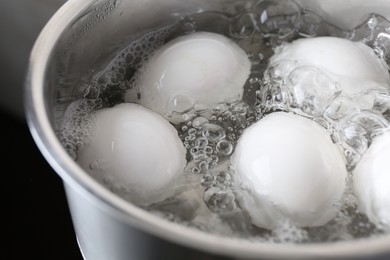 Chicken eggs boiling in saucepan, closeup view