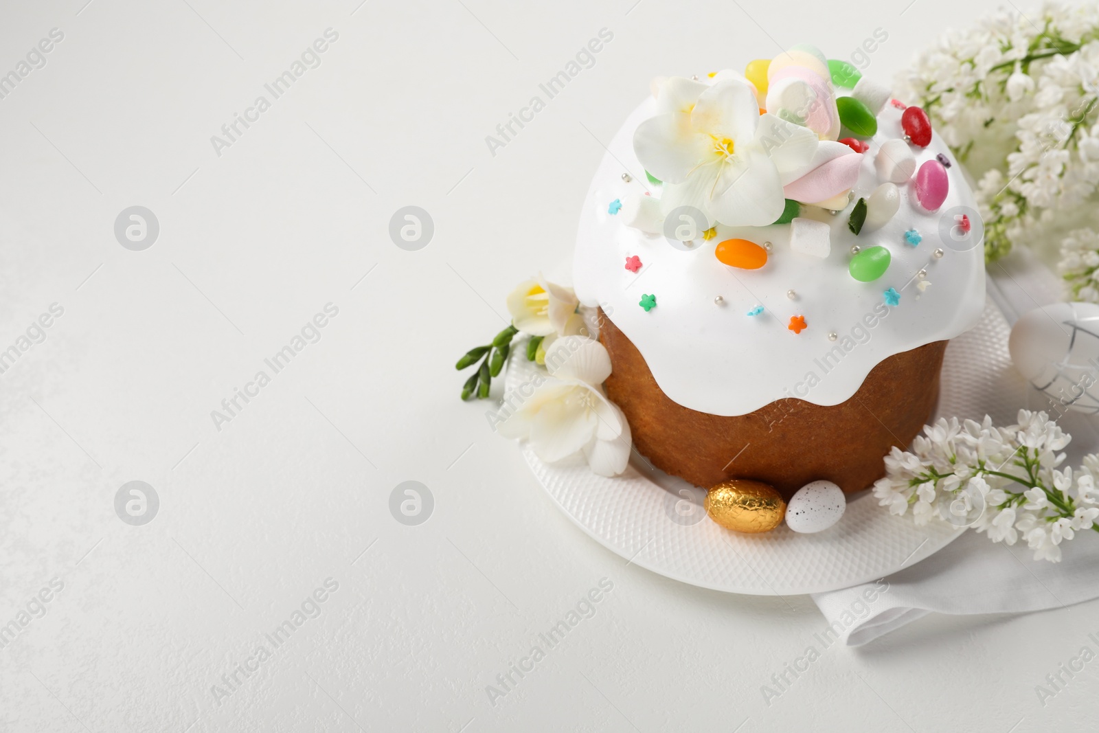 Photo of Traditional Easter cake with sprinkles, jelly beans, marshmallows and decorated eggs on white table, space for text