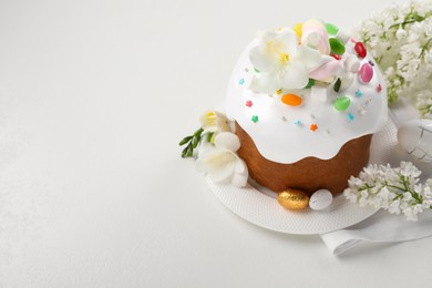 Photo of Traditional Easter cake with sprinkles, jelly beans, marshmallows and decorated eggs on white table, space for text