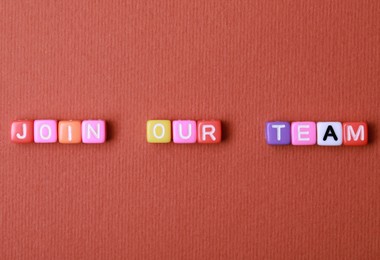 Photo of Colorful cubes with phrase Join Our Team on red background, flat lay. Recruiter searching employee