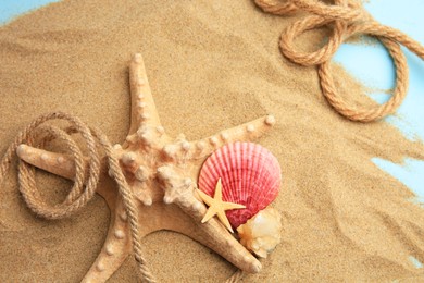 Photo of Beautiful starfishes, sea shells, rope and sand on light blue background