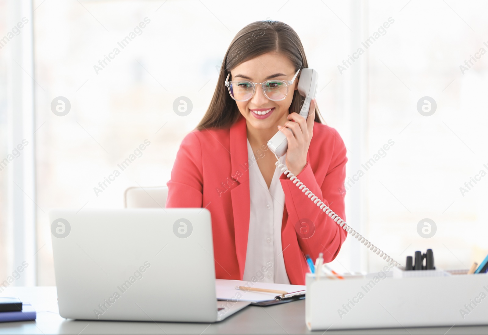 Photo of Young woman talking on phone at workplace