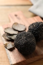 Black truffles with wooden board on table, closeup