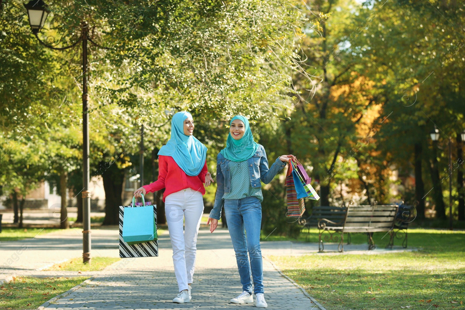 Photo of Muslim women with shopping bags walking in park