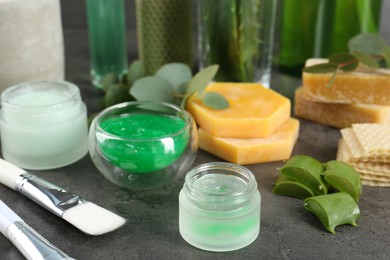 Photo of Homemade cosmetic products, fresh ingredients and brush on black table