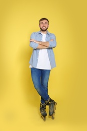 Photo of Full length portrait of young man with inline roller skates on color background