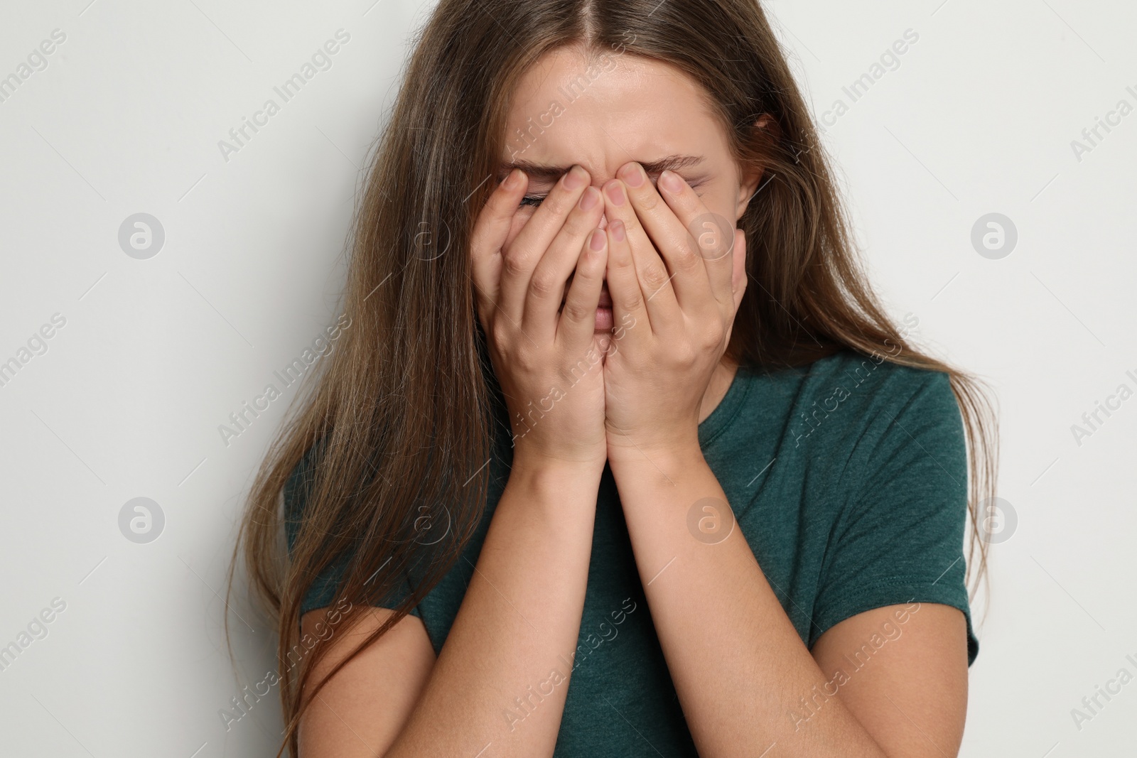 Photo of Crying young woman on light background. Stop violence