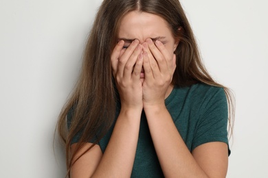 Photo of Crying young woman on light background. Stop violence