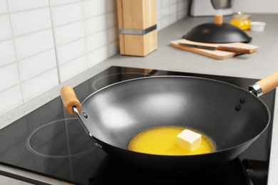 Wok pan with melted butter on stove in kitchen