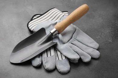 Photo of Gardening gloves and trowel on grey table