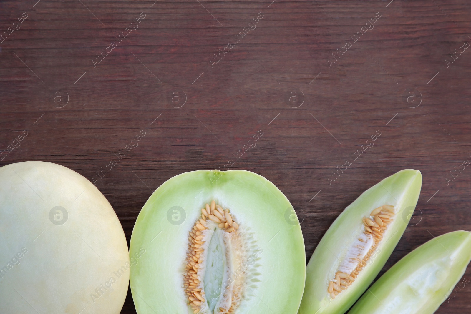 Photo of Cut tasty ripe melon on wooden table, flat lay. Space for text