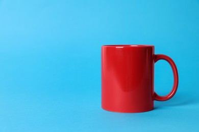 Photo of One red ceramic mug on light blue background. Space for text