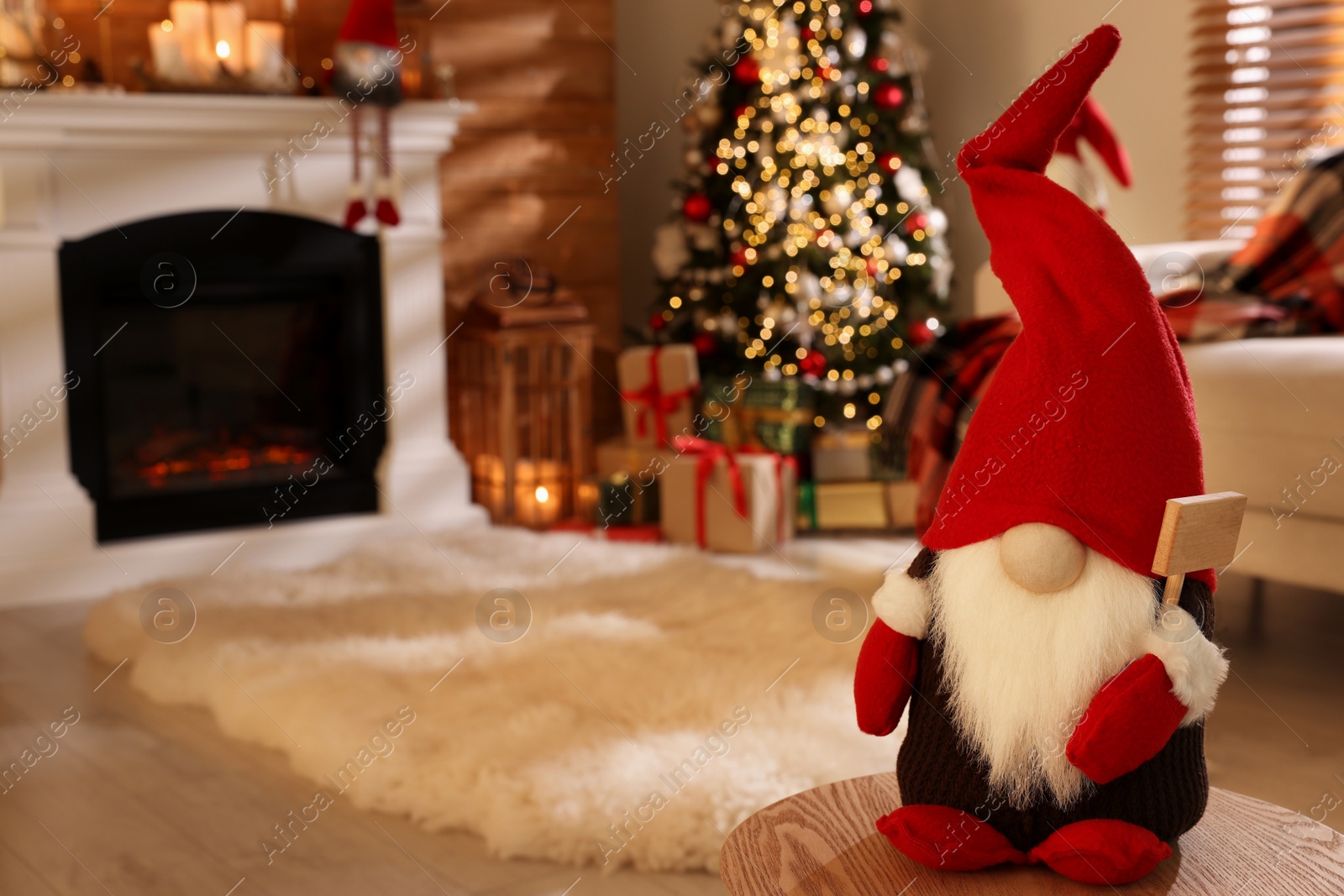 Photo of Cute Christmas gnome on wooden table in room with festive decorations. Space for text