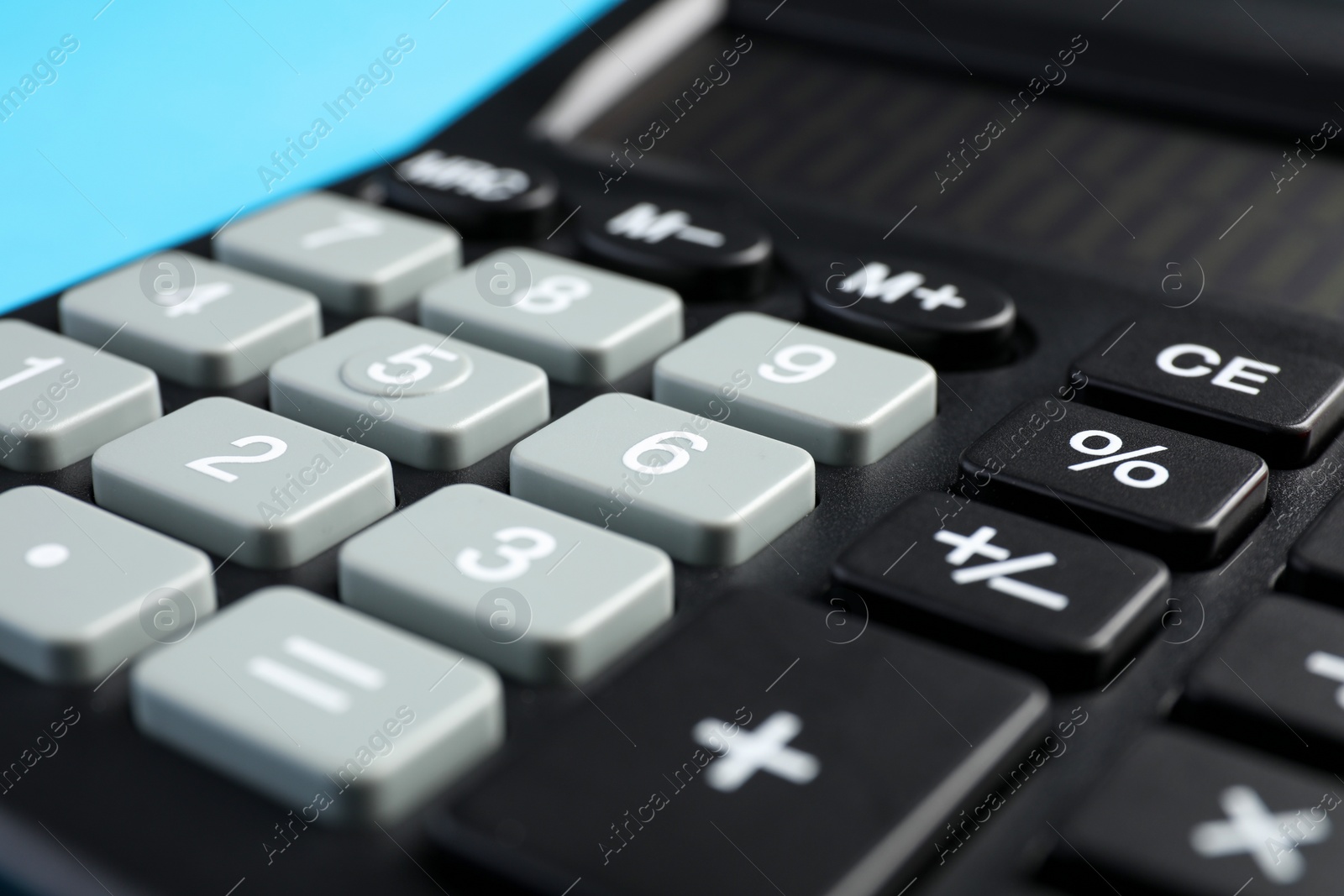 Photo of Calculator on light blue background, closeup. Office equipment