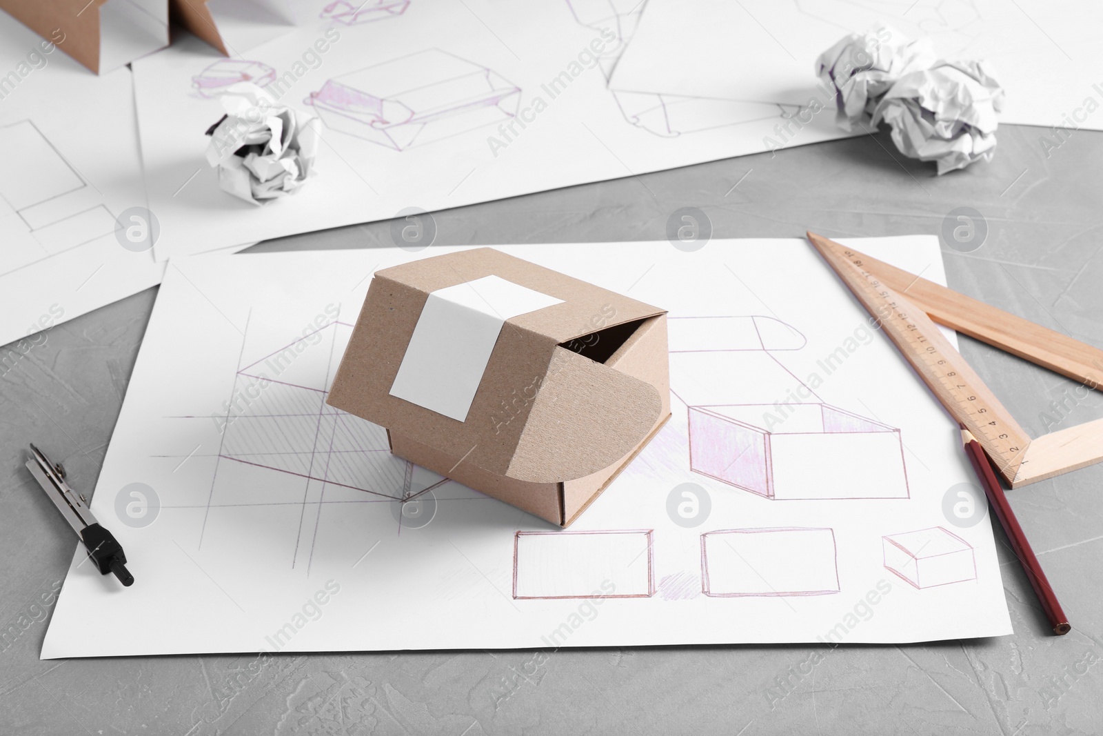 Photo of Creating packaging design. Drawing, box and stationery on blue textured table, closeup