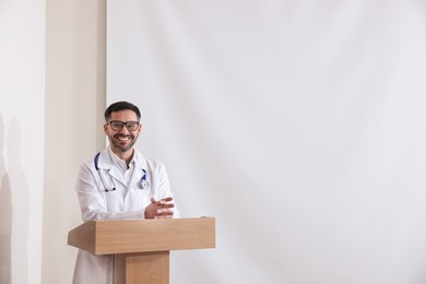 Doctor giving lecture near projection screen in conference room, space for text