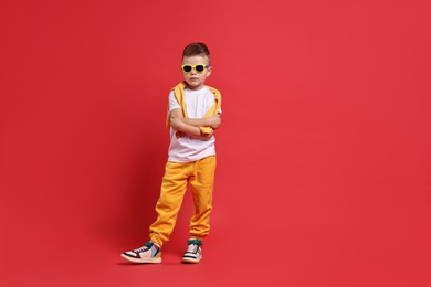 Photo of Happy little boy dancing on red background. Space for text