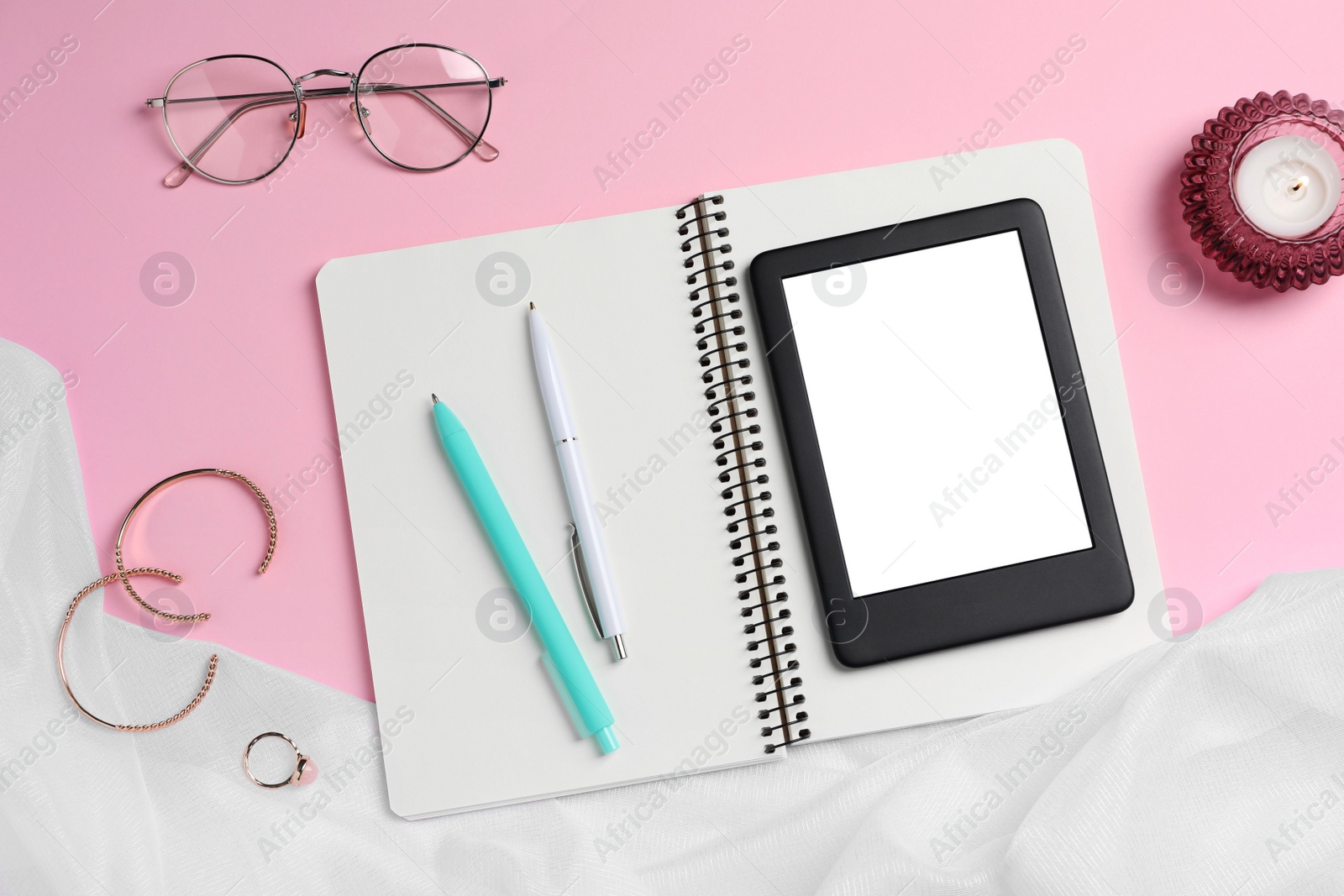 Photo of Flat lay composition with e-book reader, notebook and glasses on pink background. Space for text