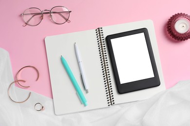 Photo of Flat lay composition with e-book reader, notebook and glasses on pink background. Space for text