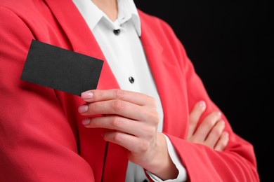 Woman holding blank business card on black background, closeup. Space for text