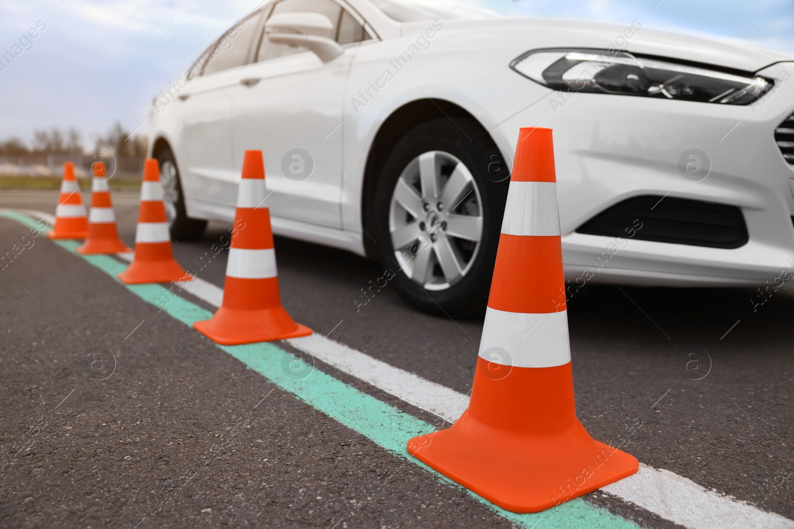 Photo of Modern car on test track with traffic cones, closeup. Driving school