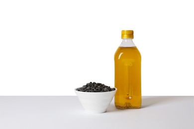 Photo of Bottle of cooking oil and sunflower seeds on white background, space for text