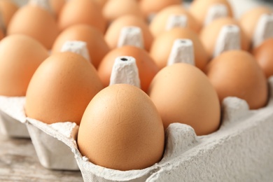 Raw chicken eggs in carton, closeup view