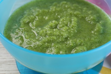 Healthy baby food. Bowl with tasty broccoli puree on white table, closeup