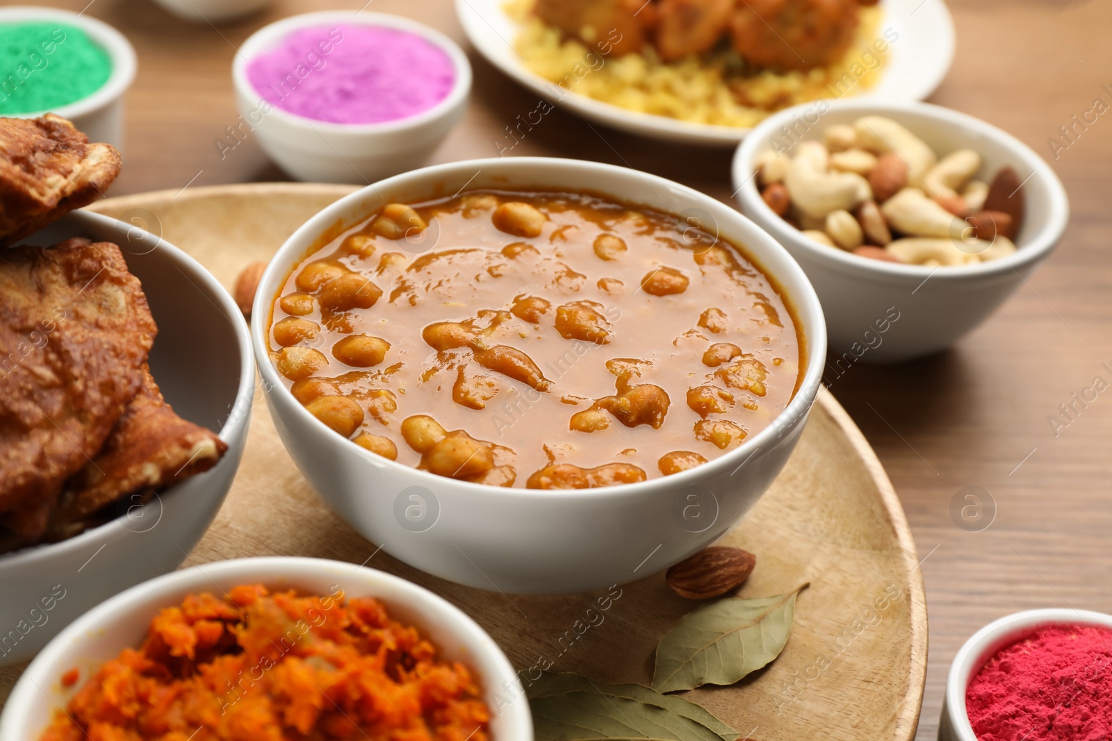 Photo of Traditional Indian food and color powders on wooden table, closeup. Holi festival celebration