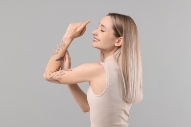 Photo of Portrait of beautiful tattooed woman on gray background