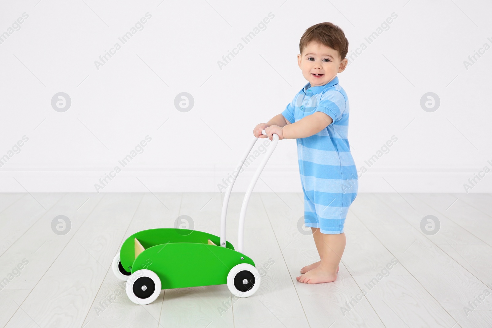 Photo of Cute baby playing with toy walker, indoors